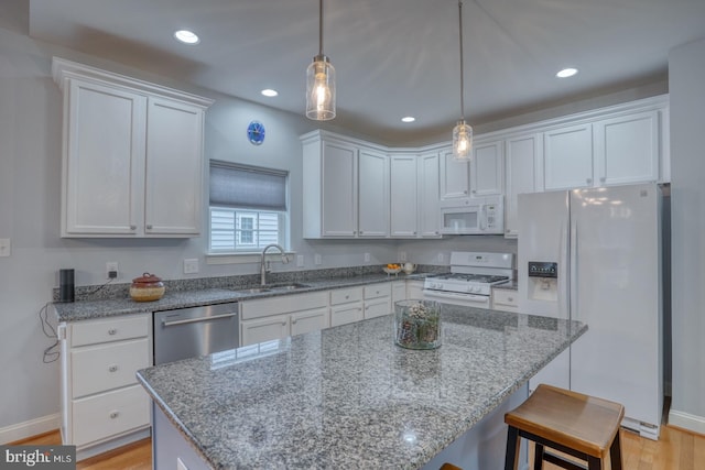 kitchen featuring white appliances, sink, a kitchen island, light hardwood / wood-style floors, and white cabinetry