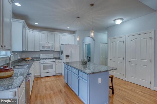 kitchen featuring white appliances, a kitchen island, sink, pendant lighting, and white cabinetry