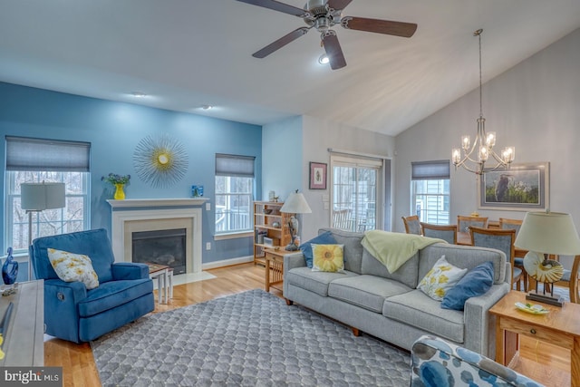 living room with vaulted ceiling, light hardwood / wood-style floors, and ceiling fan with notable chandelier