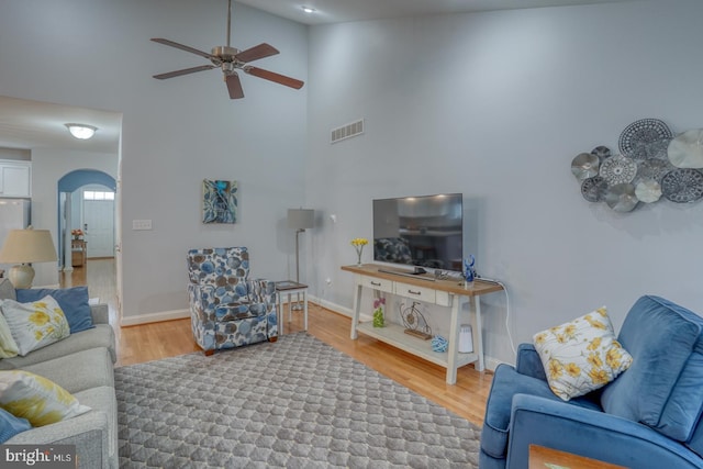 living room featuring wood-type flooring, a towering ceiling, and ceiling fan