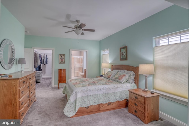 bedroom featuring a walk in closet, ensuite bathroom, light colored carpet, ceiling fan, and a closet