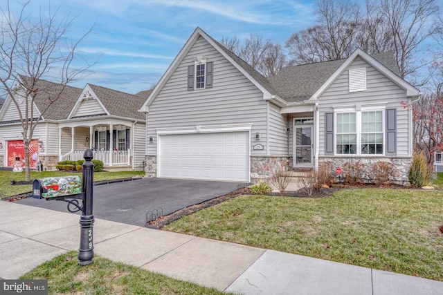 view of front of property featuring covered porch, a garage, and a front yard