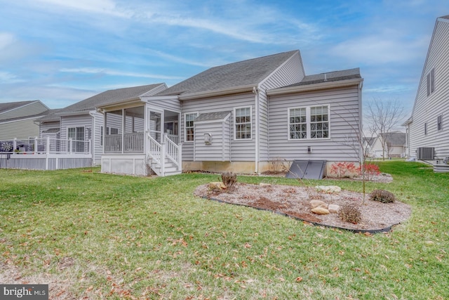 rear view of house featuring a lawn, a sunroom, and central AC unit