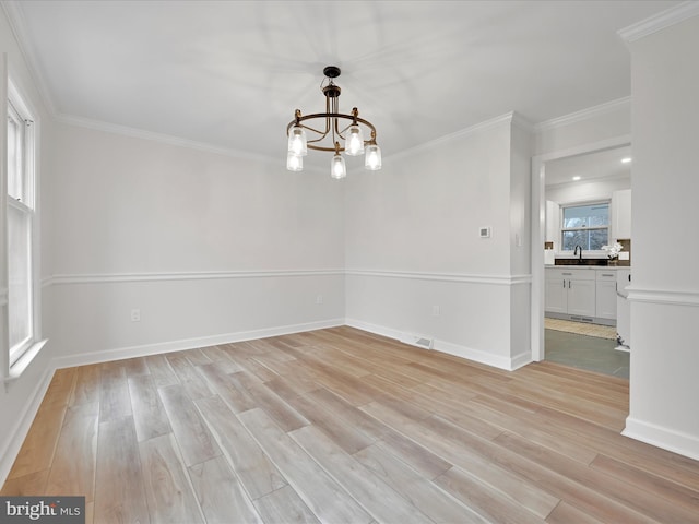 unfurnished room with a notable chandelier, crown molding, sink, and a wealth of natural light