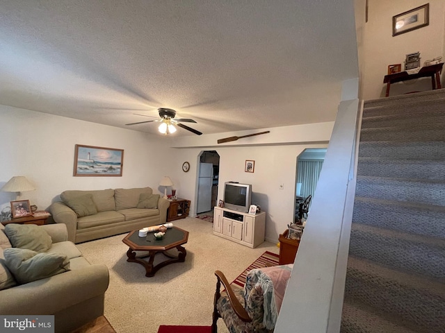 living room with arched walkways, ceiling fan, a textured ceiling, and light carpet