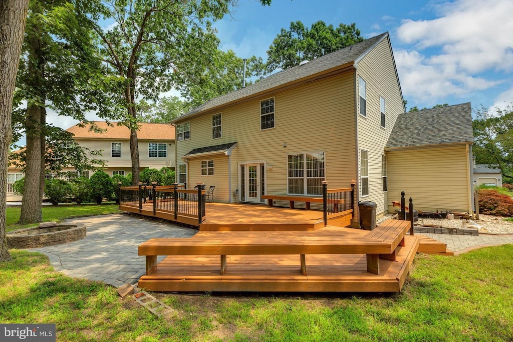 back of property featuring a fire pit, a yard, a patio, and a wooden deck