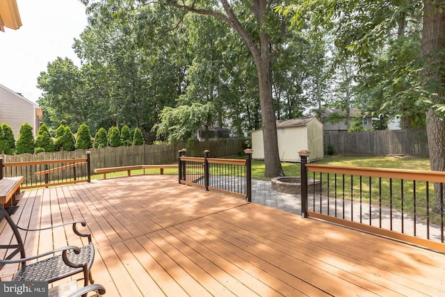 wooden terrace featuring a yard, a shed, and a fire pit