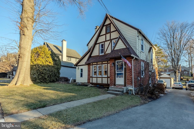 tudor-style house featuring a front yard, a garage, and an outdoor structure