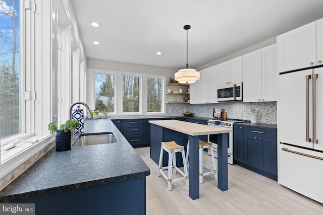 kitchen featuring white appliances, a breakfast bar area, a center island, blue cabinetry, and open shelves