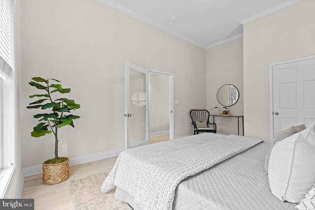 bedroom with light wood-style floors, crown molding, and baseboards