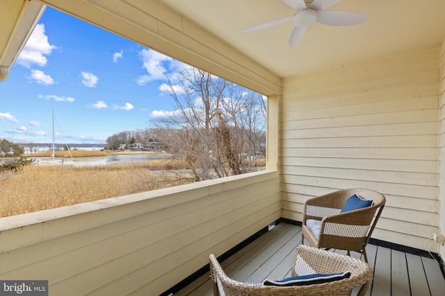 balcony featuring a water view and a ceiling fan