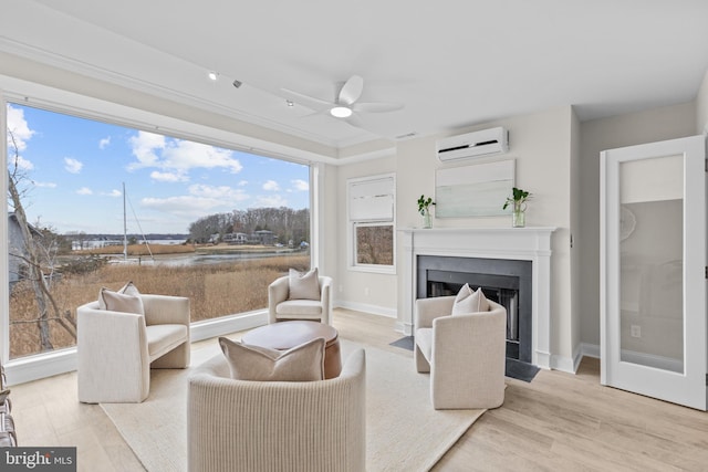 living room with light wood-style floors, a fireplace with flush hearth, ceiling fan, and a wall mounted air conditioner