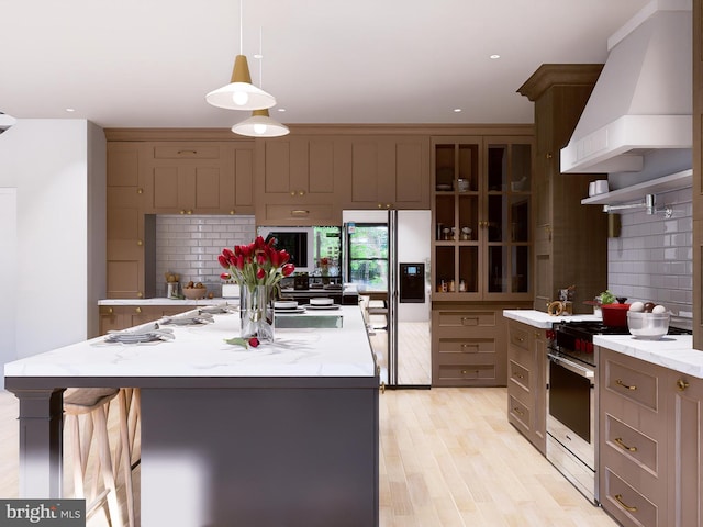 kitchen featuring decorative light fixtures, refrigerator with ice dispenser, wall chimney range hood, and a large island