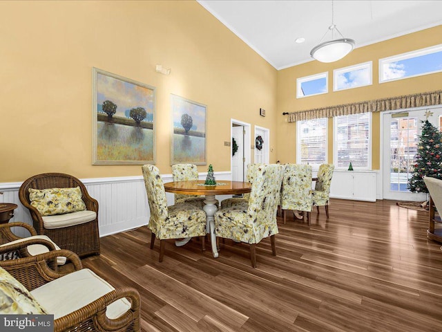 dining space with a high ceiling, dark hardwood / wood-style floors, and ornamental molding