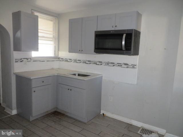 kitchen with sink, light wood-type flooring, and backsplash