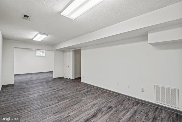 basement featuring dark hardwood / wood-style floors and a textured ceiling