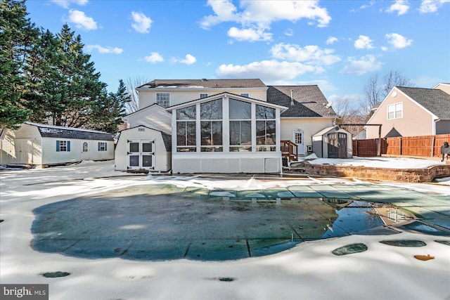 back of property with a covered pool, a sunroom, and a storage shed