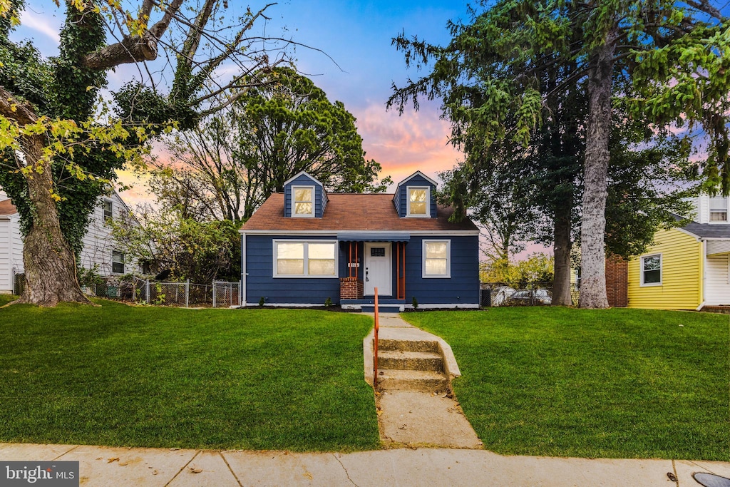 cape cod house featuring a lawn