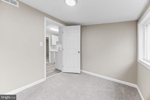 unfurnished bedroom featuring light carpet and multiple windows