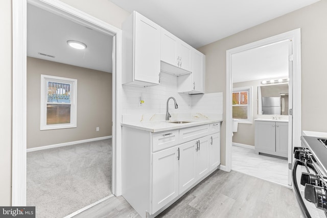 kitchen with white cabinets, light hardwood / wood-style floors, stainless steel range oven, and sink