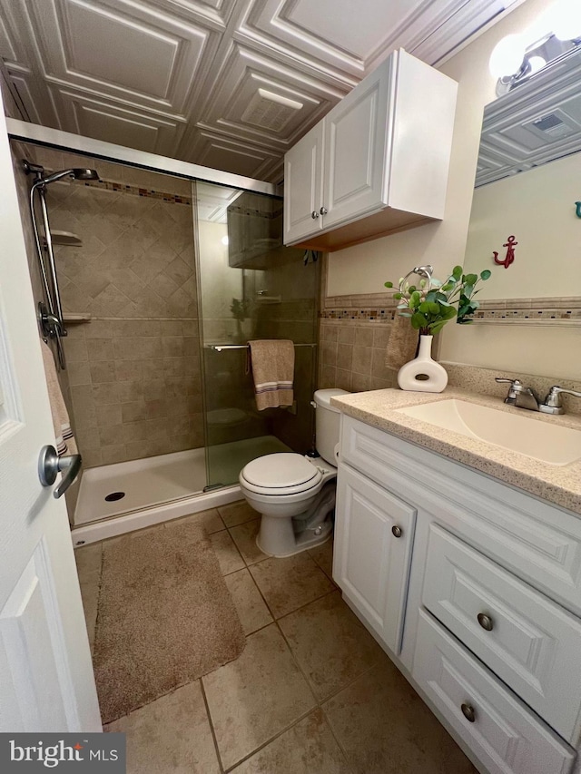 bathroom featuring toilet, a shower with door, vanity, and tile patterned flooring