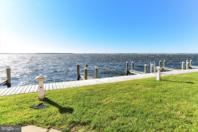 view of dock with a water view and a yard