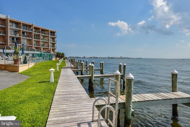 view of dock with a lawn and a water view