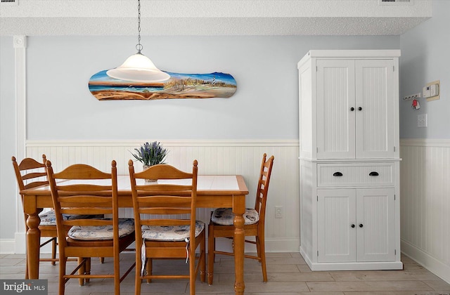 dining area with light wood-type flooring and a textured ceiling