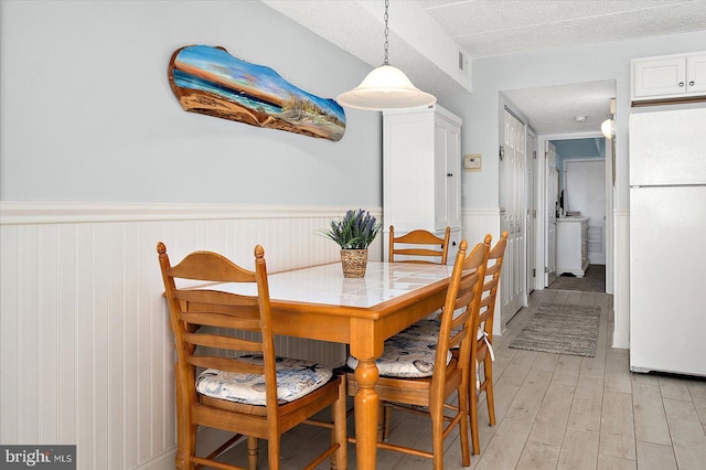 dining space with light hardwood / wood-style floors and a textured ceiling