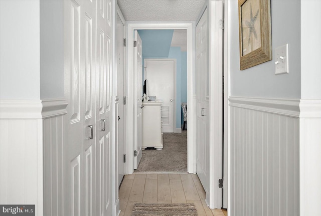 hall with a textured ceiling and light carpet