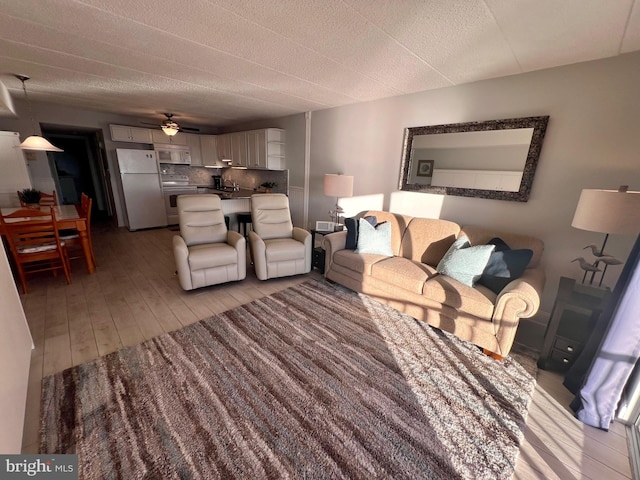 living room with ceiling fan, sink, and light wood-type flooring