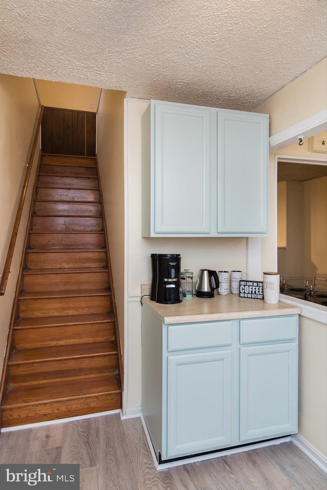 stairway with a textured ceiling and hardwood / wood-style flooring