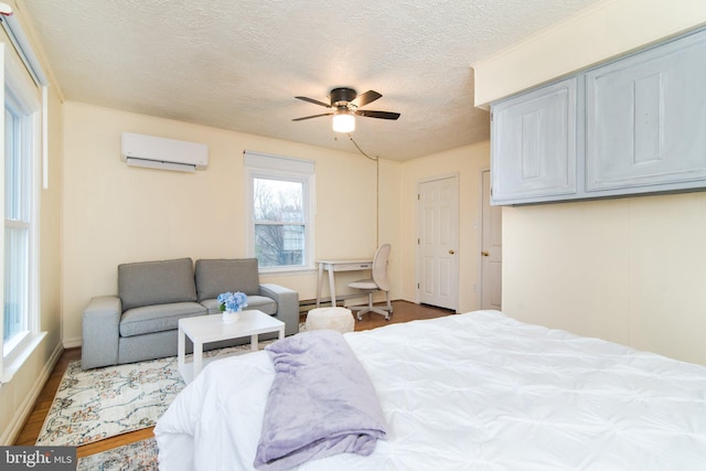 bedroom with a wall mounted air conditioner, a baseboard heating unit, hardwood / wood-style flooring, ceiling fan, and a textured ceiling