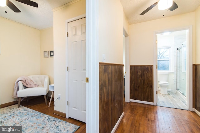 interior space featuring connected bathroom, ceiling fan, dark wood-type flooring, and a textured ceiling