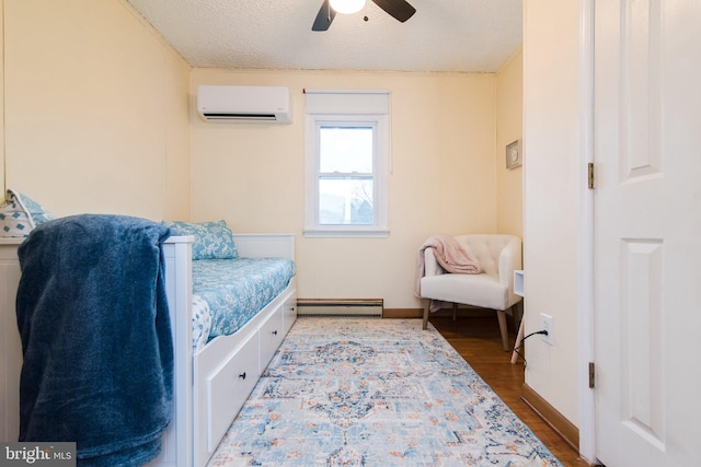 bedroom featuring a textured ceiling, ceiling fan, a baseboard heating unit, wood-type flooring, and an AC wall unit