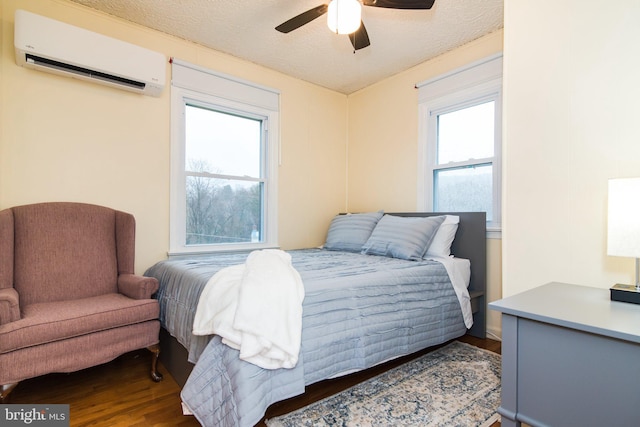 bedroom with an AC wall unit, ceiling fan, a textured ceiling, and dark hardwood / wood-style floors