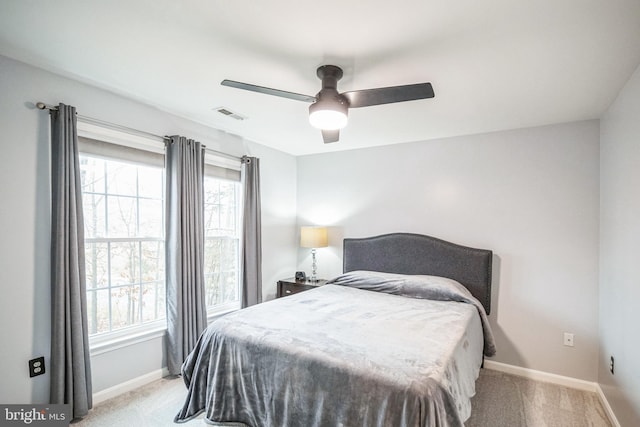 bedroom featuring ceiling fan, light colored carpet, and multiple windows