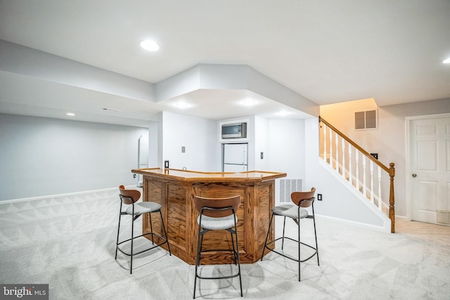 bar with white refrigerator, light colored carpet, and stainless steel microwave