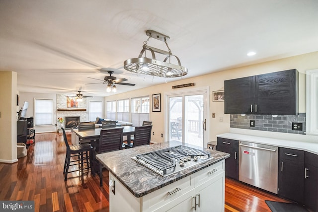 kitchen with dark wood-type flooring, stainless steel appliances, a center island, and white cabinets