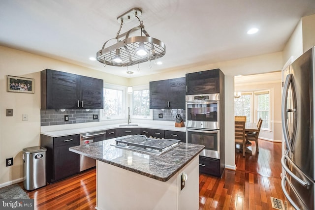 kitchen with appliances with stainless steel finishes, dark hardwood / wood-style floors, sink, a center island, and plenty of natural light