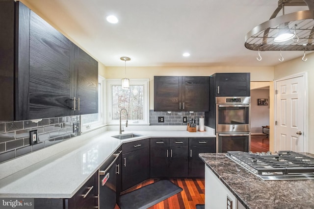 kitchen featuring sink, backsplash, stainless steel appliances, dark hardwood / wood-style flooring, and decorative light fixtures