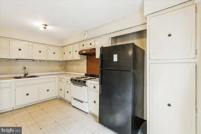 kitchen featuring black fridge, white cabinetry, sink, and white range