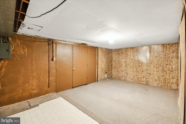 basement with electric panel, wood walls, and light colored carpet