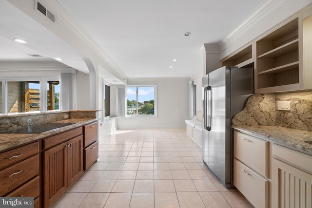 kitchen with light stone countertops, black electric cooktop, tasteful backsplash, light tile patterned flooring, and stainless steel refrigerator