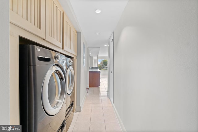 washroom featuring washing machine and dryer, light tile patterned floors, and cabinets