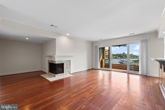 unfurnished living room featuring a premium fireplace, wood-type flooring, and ornamental molding