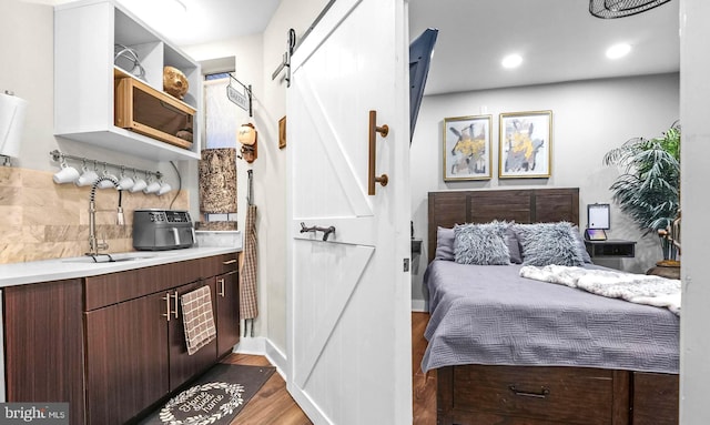 bedroom featuring a barn door, sink, and dark wood-type flooring