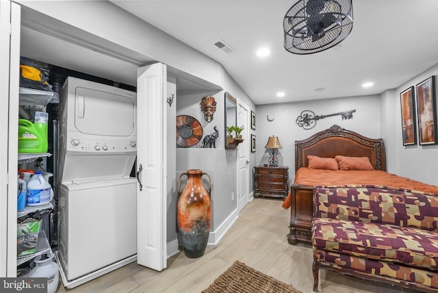 bedroom featuring light wood-type flooring and stacked washer / drying machine