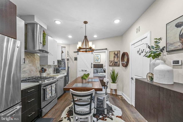 kitchen with tasteful backsplash, dark wood-type flooring, wall chimney exhaust hood, and stainless steel appliances