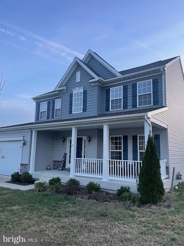 view of front facade featuring a porch, a garage, and a front yard